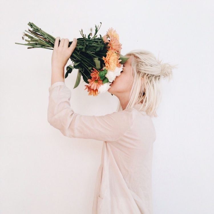 Profile photo of girl holding flowers to cover her face